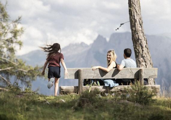 A family sits on a bench in the mountains and enjoys the picturesque view 