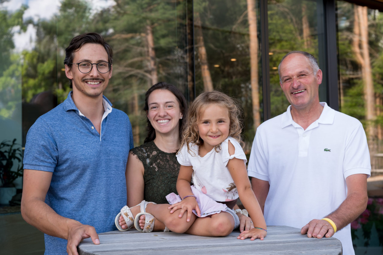 Eine Familie posiert für ein Foto vor dem Gebäude der SchartnerAlm.