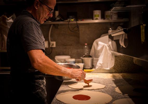 Un uomo prepara la pizza nella pizzeria SchartnerAlm