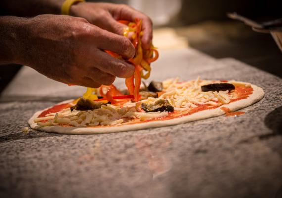 Una persona prepara una pizza nella Pizzeria SchartnerAlm