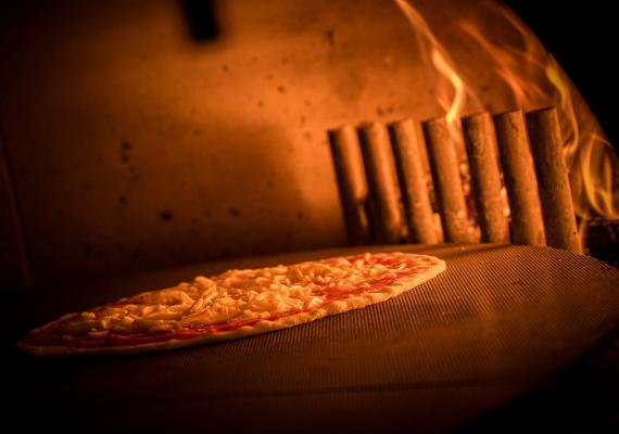 A pizza is baked in a wood-fired oven at the Pizzeria SchartnerAlm