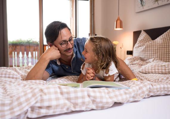 A man and a little girl lie relaxed on a bed and enjoy a quiet moment together